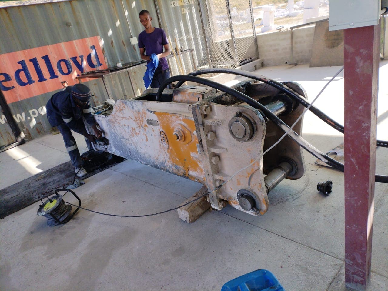 Workshop team carrying out repair work on a large hammer attachment