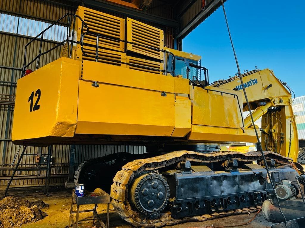 Large yellow excavator positioned inside a workshop bay