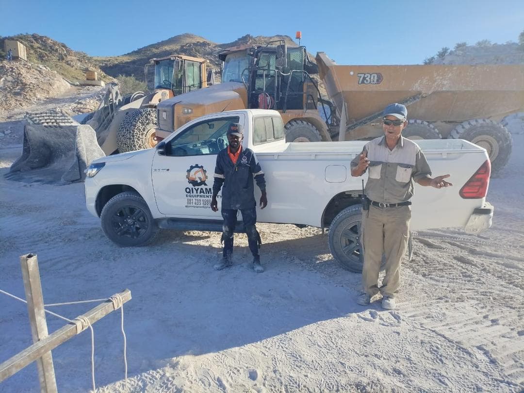 Qiyam team and support vehicle positioned near loader and dump truck equipment