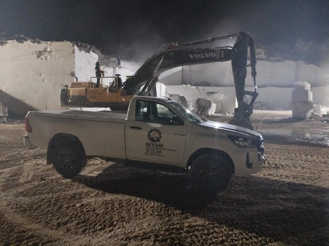 Qiyam support vehicle beside a Volvo excavator working at night on site