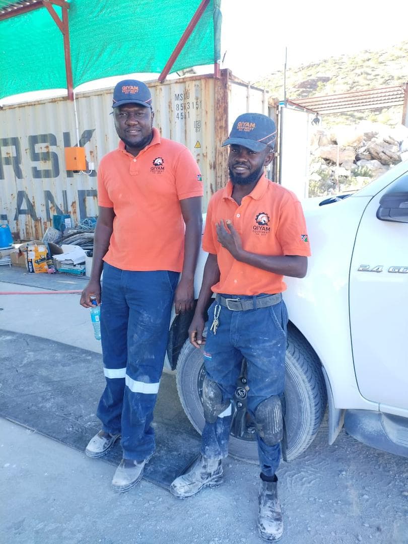 Qiyam technicians in branded workwear standing at site